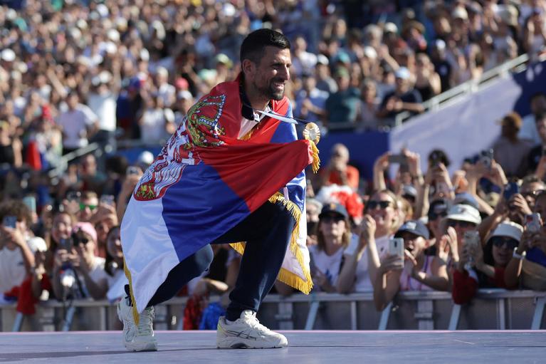Novak Djokovic avvolto nella bandiera serba dopo l'oro olimpico a Parigi (Getty Images)